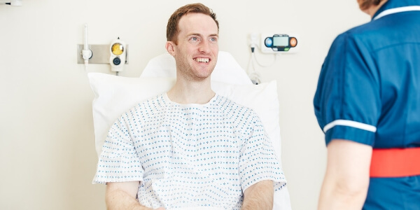 Male patient on hospital bed smiling