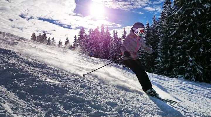 Skier wearing goggles and helmet on a slope blue sky